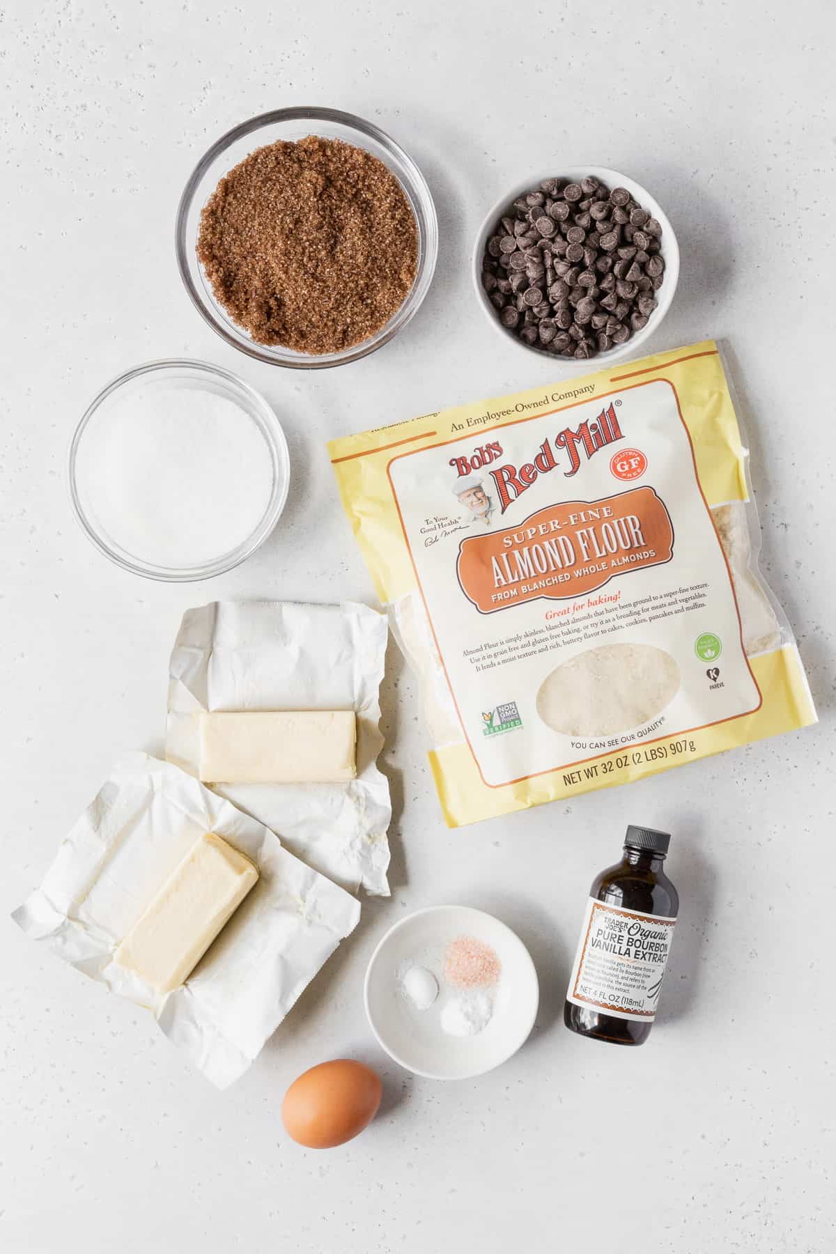 Ingredients to make almond flour cookies laid out on a light grey surface.