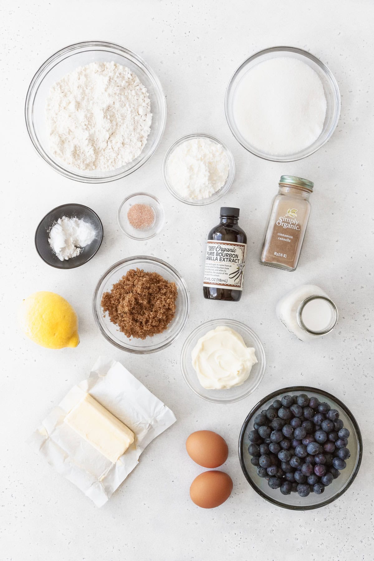 Ingredients for blueberry coffee cake measured out into bowls on a white surface.