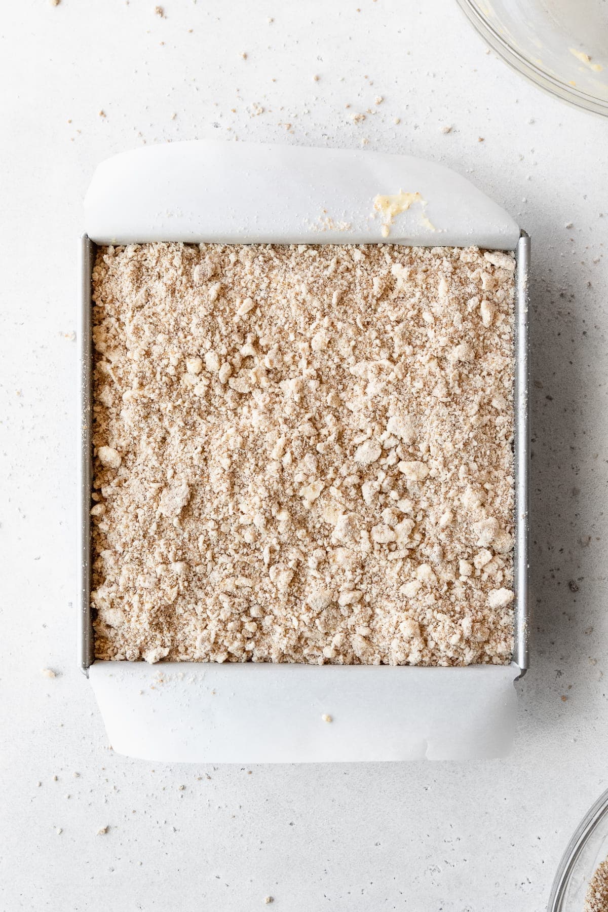 Cake batter topped with crumb topping in a square pan ready to be baked.