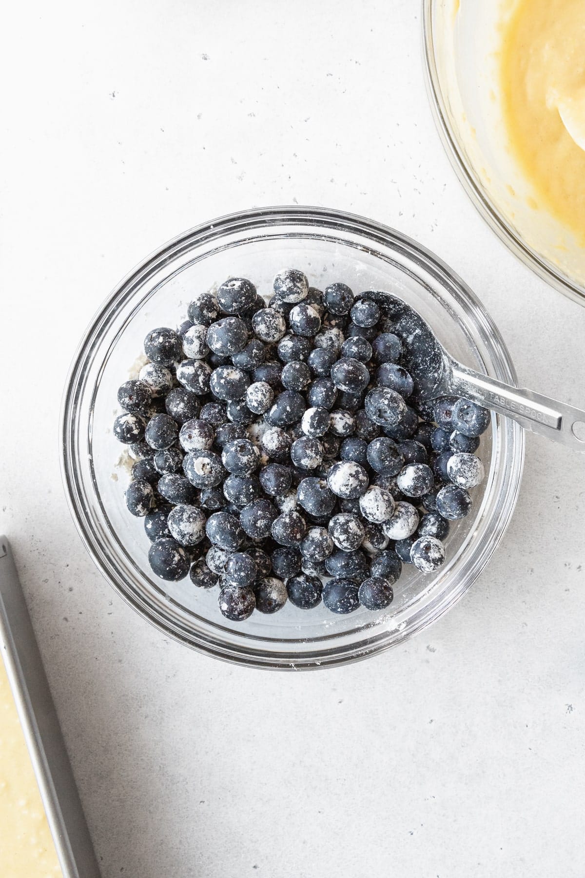 Fresh blueberries in a glass bowl tossed with flour.