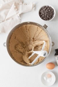 Creamed butter and sugar in a metallic bowl with a white beater inside.