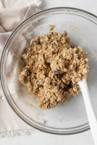 Gluten free oatmeal cookie dough in a glass bowl with a white silicone spatula.