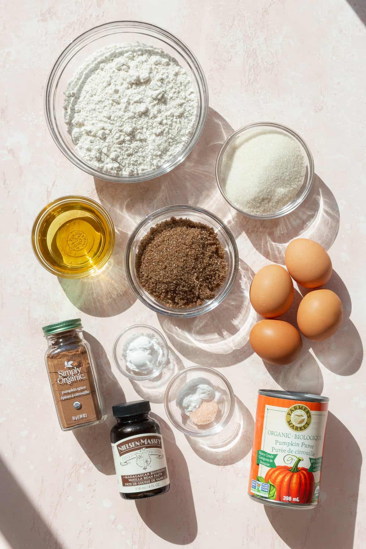 Ingredients for pumpkin bars on a pink surface.