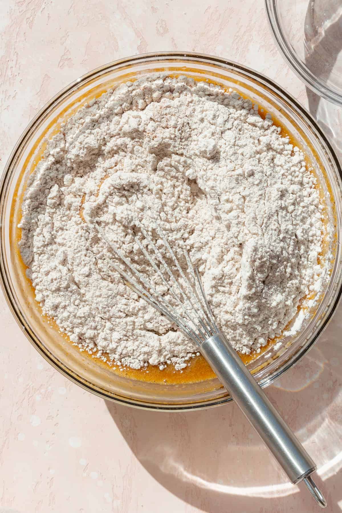 Dry ingredients whisked into the wet ingredients in a glass bowl.