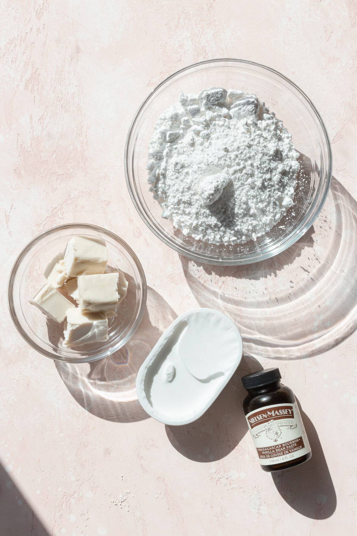 Ingredients for cream cheese frosting on a pink surface.