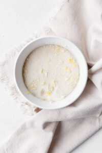 A white dish on a linen with lemon sugar inside.
