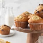 Gluten-free banana muffins on a wooden cake stand.