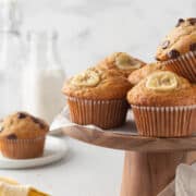 Gluten-free banana muffins on a wooden cake stand.
