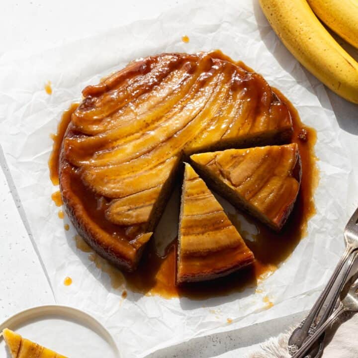 A banana upside down cake on parchment paper with two slices cut out.