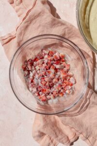 Diced strawberries coated in flour in a glass bowl.