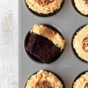 A chocolate cupcake in a muffin tin with peanut butter frosting.