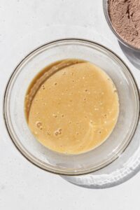 Eggs, milk, sugar, oil, and butter mixed together in a bowl.