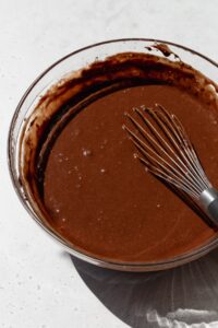 Gluten free chocolate cake batter in a bowl with a whisk.
