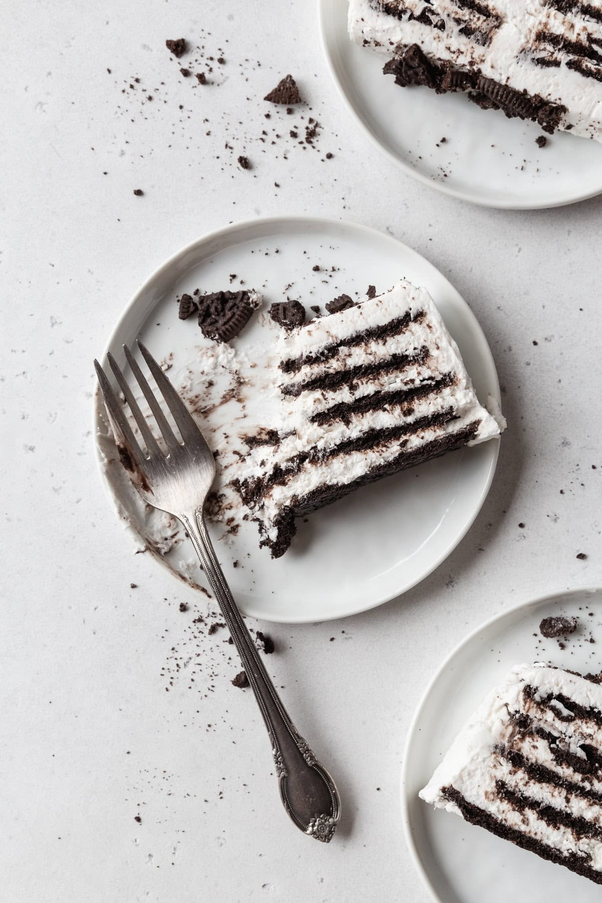 A partially eaten slice of icebox cake on a white plate with a fork.