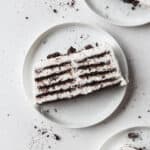 A slice of icebox cake on a white plate with Oreo crumbs.