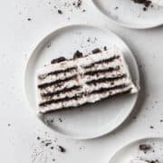 A slice of icebox cake on a white plate with Oreo crumbs.