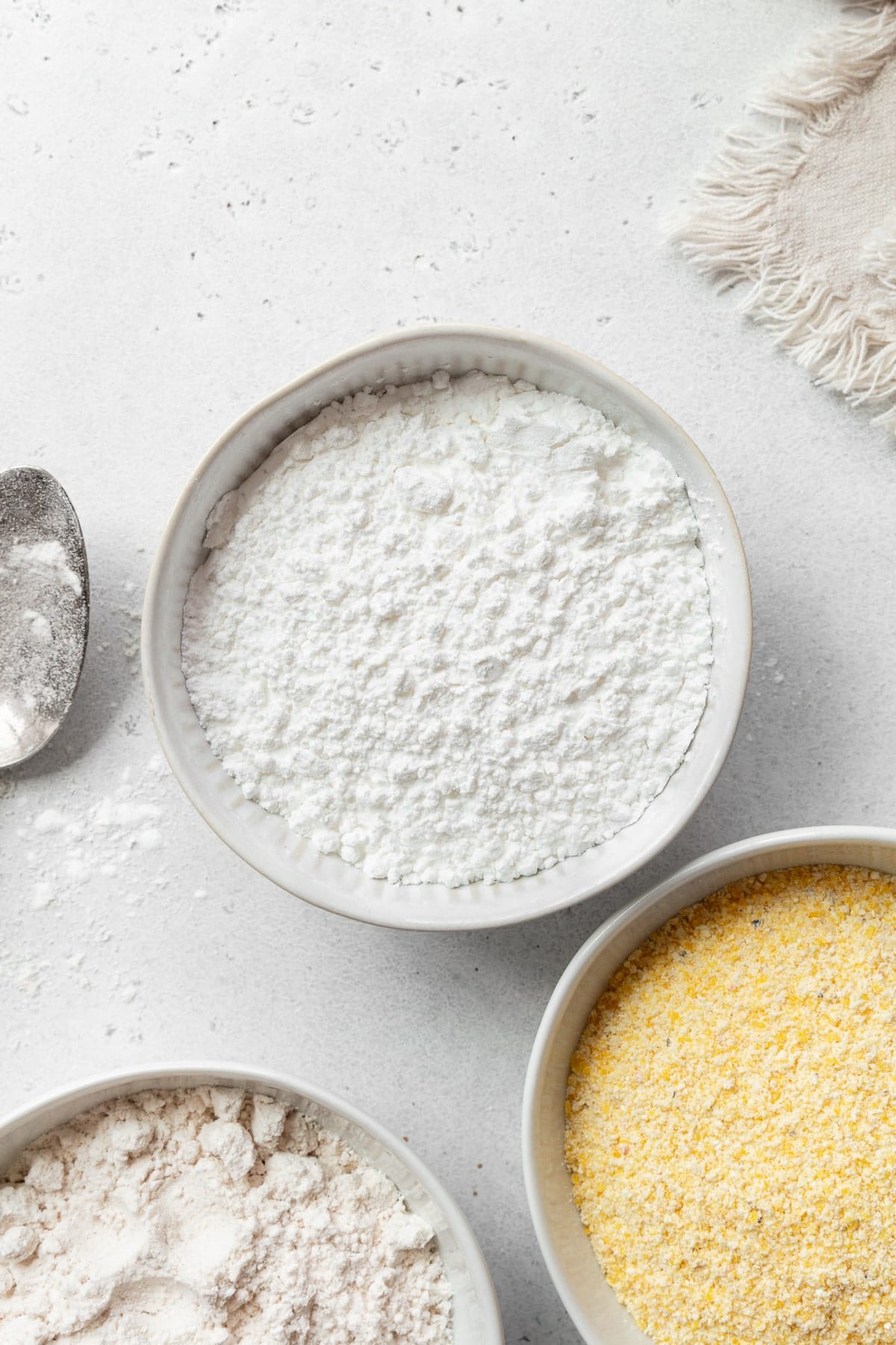 A bowl of rice flour with a bowl of cornmeal on the side.