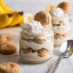 Two jars of vegan banana pudding with bananas in the background.