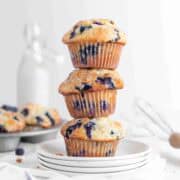 A stack of three blueberry muffins on white plates.