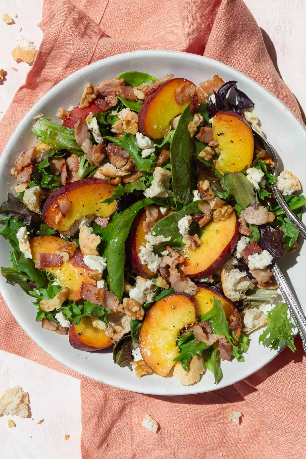 Peach salad in a white bowl on a peach colored background.