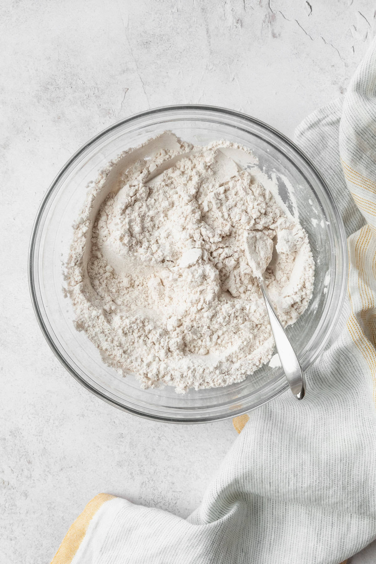 Dry ingredients in a glass bowl with a spoon.