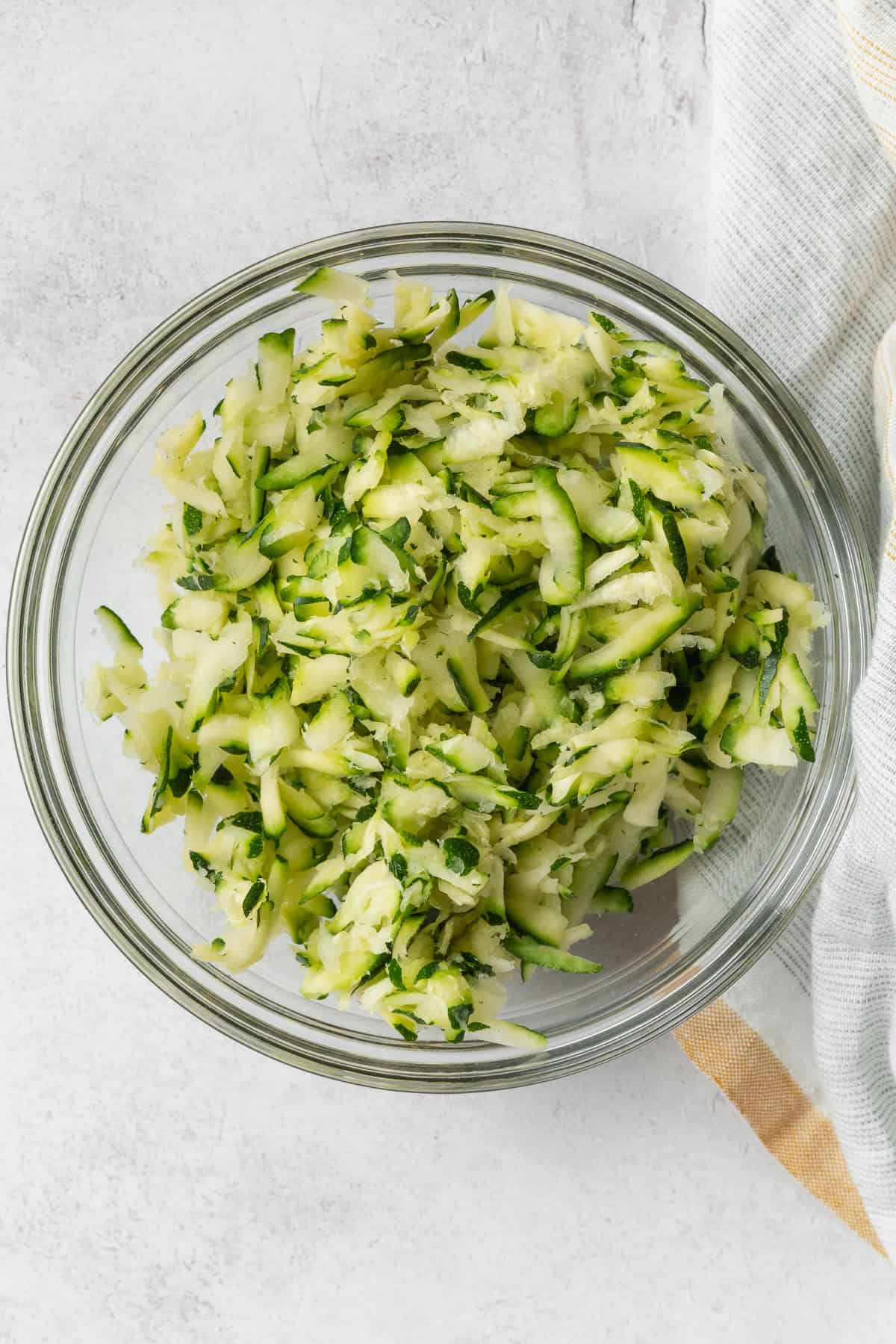 A glass bowl of grated zucchini.