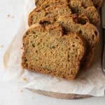 Slices of gluten-free zucchini bread on a wooden board lined with parchment paper.