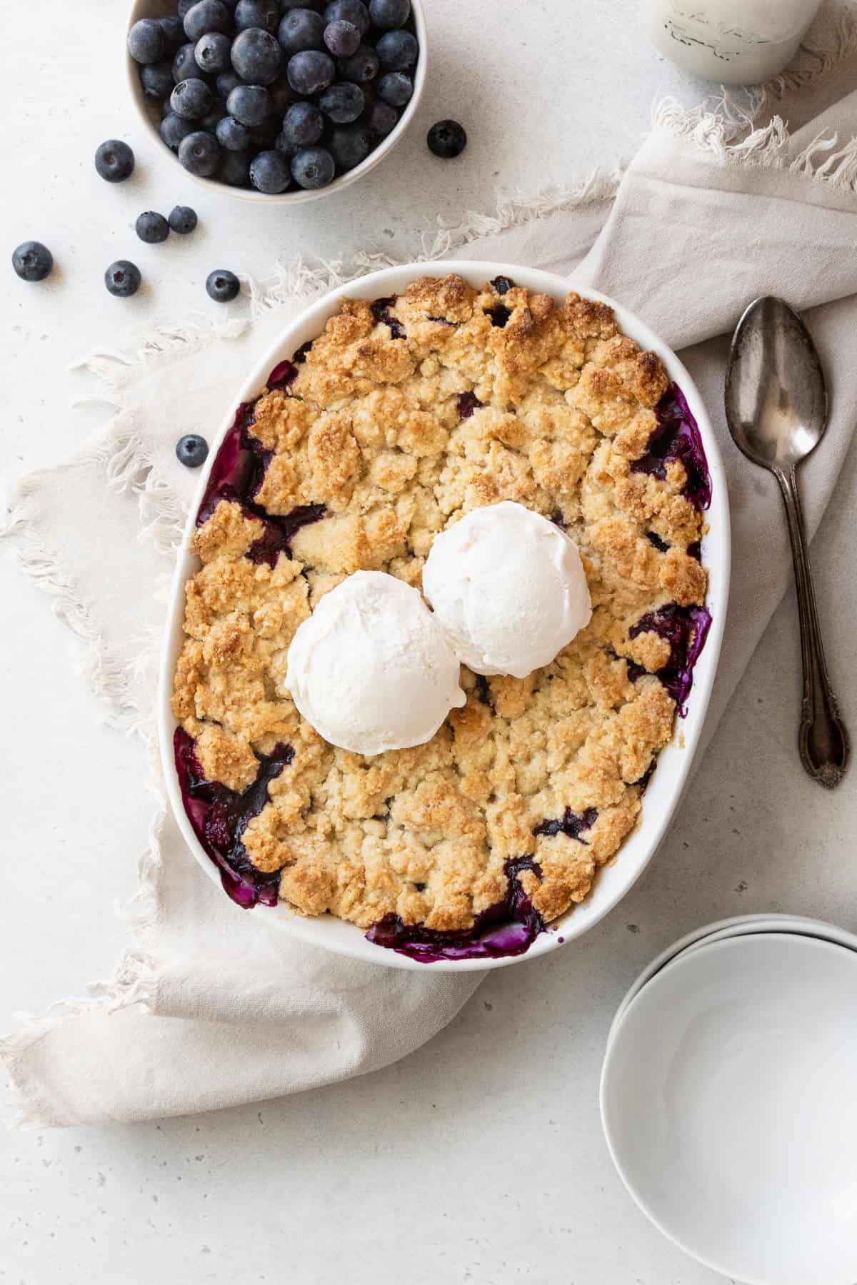 Blueberry cobbler with two scoops of vanilla ice cream on top.