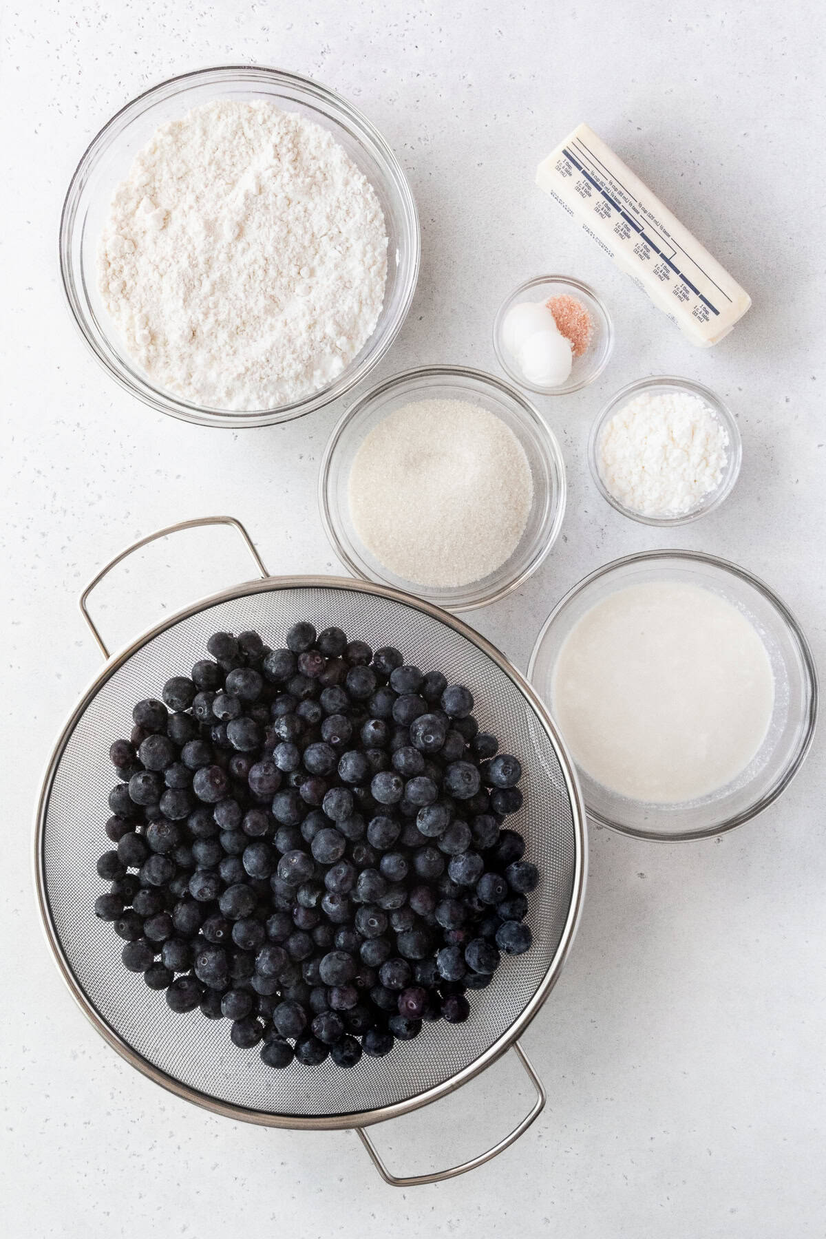 Ingredients for blueberry cobbler recipe measured out into bowls.